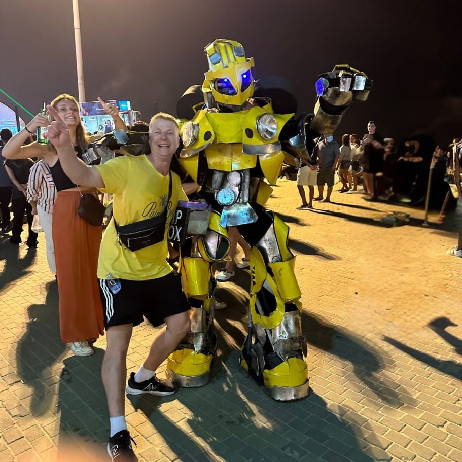 Besucher posieren mit einem gelben Roboter-Charakter auf dem Pattaya Music Festival 2024 – fröhliche Festivalstimmung in Thailand