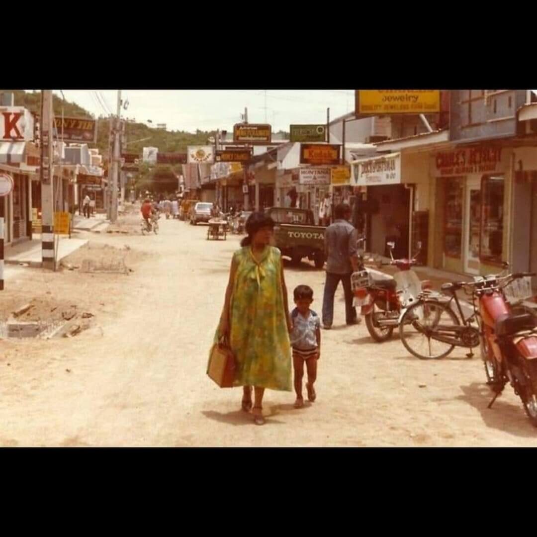 Historische Aufnahme der Walking Street Pattaya aus den 1970er Jahren mit ungepflasterter Straße, Geschäften und Motorrädern.