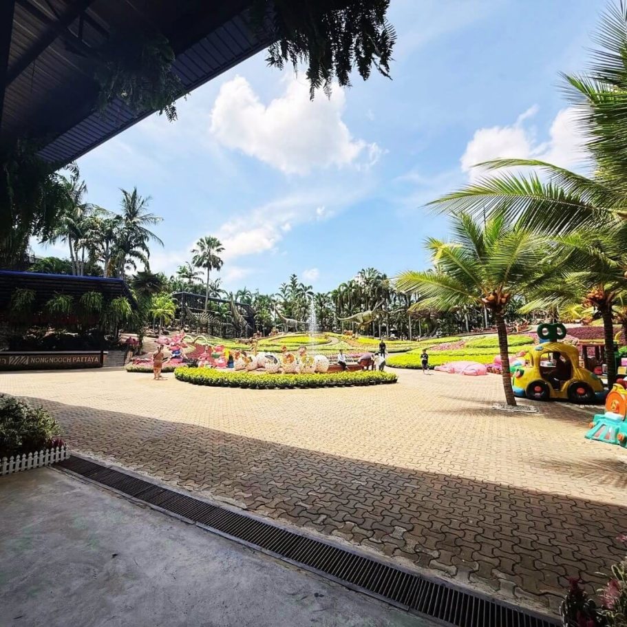 Dino-Park im Nong Nooch Garden für Kinder und Familien Eingangsbereich des Dinosaurierparks im Nong Nooch Garden mit Palmen, bunter Deko und Kinderfahrzeugen.