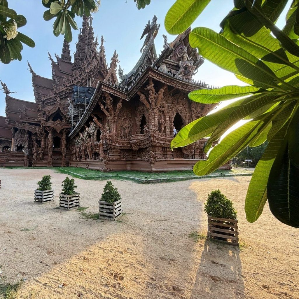 Sanctuary of Truth - Pattayas spirituelles Holzkunstwerk Sanctuary of Truth Holztempel in Pattaya mit Schnitzereien, Pflanzen und blauem Himmel