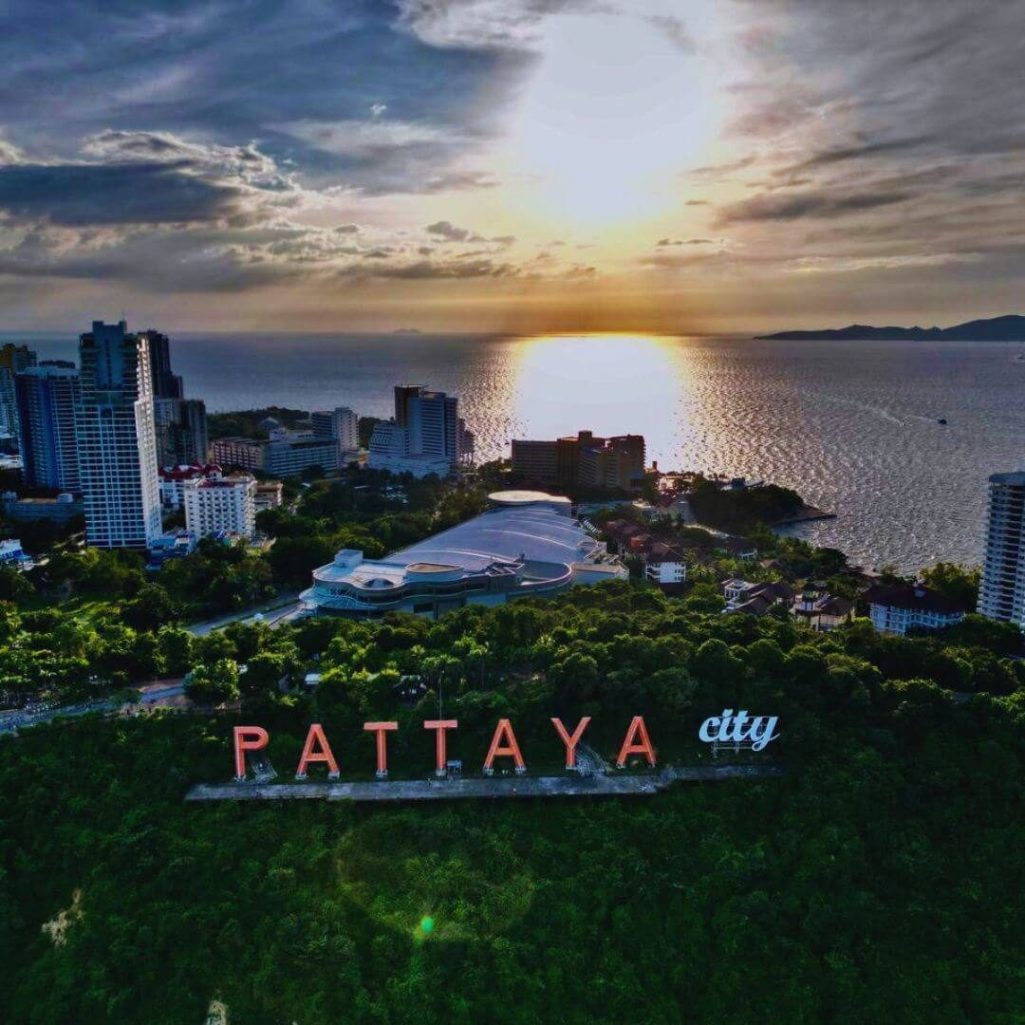 Pattaya City Schriftzug mit Blick auf die Stadt und das Meer bei Sonnenuntergang.