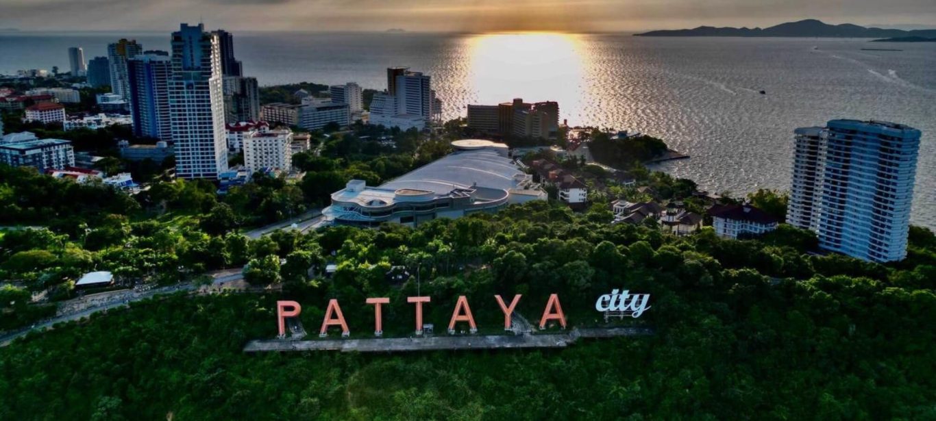 Sonnenuntergang über Pattayas Küste Luftaufnahme von Pattaya mit Meer, Küste, Gebäuden und dem Schriftzug Pattaya City