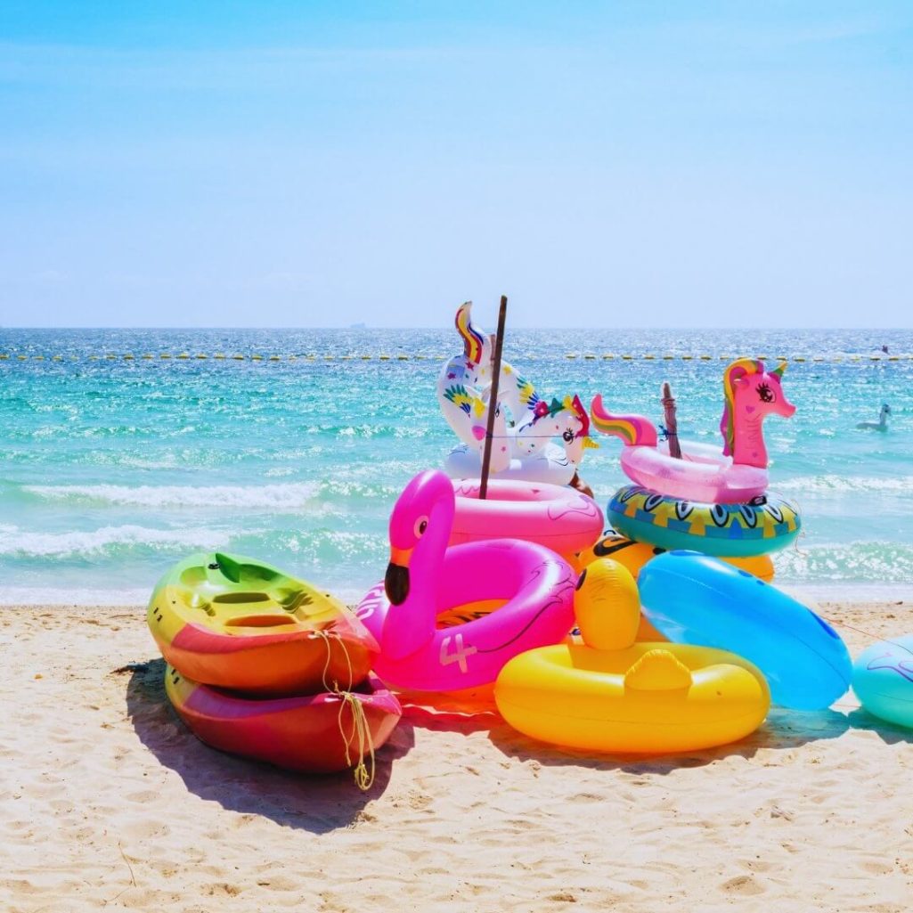 Traumhafter Strand auf Koh Larn mit türkisfarbenem Wasser und bunten Schwimmreifen – ein Paradies für Badeurlauber.