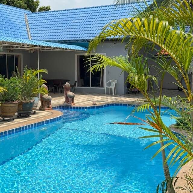 Pool Villa mit Außenbereich Poolbereich einer Villa mit blauem Swimmingpool, Palmen, Sitzbereich und Gebäude im Hintergrund