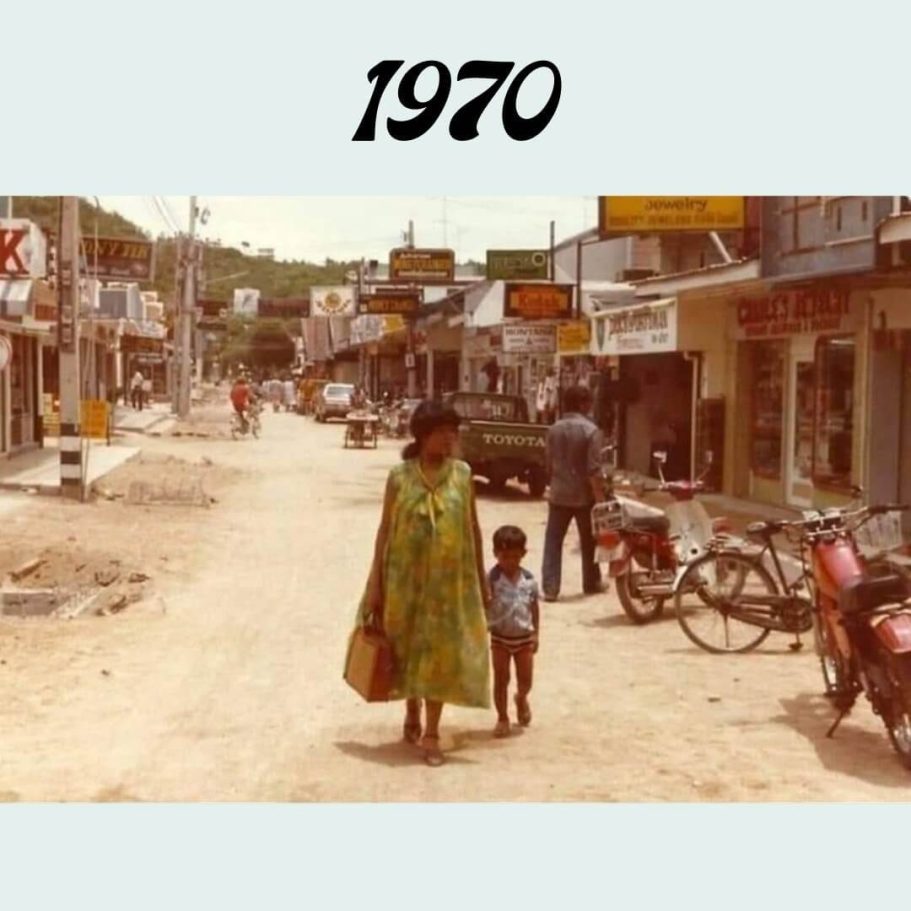 Walking Street Geschichte 1970: Die frühen Anfänge Walking Street Pattaya 1970: Eine Frau mit Kind auf der ungepflasterten Straße mit ersten Geschäften und Motorrädern