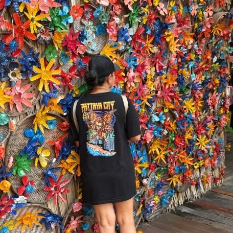 Traumhafte Fotomotive Person vor einer bunten Wand mit vielen farbigen Plastikblumen und Dekorationen