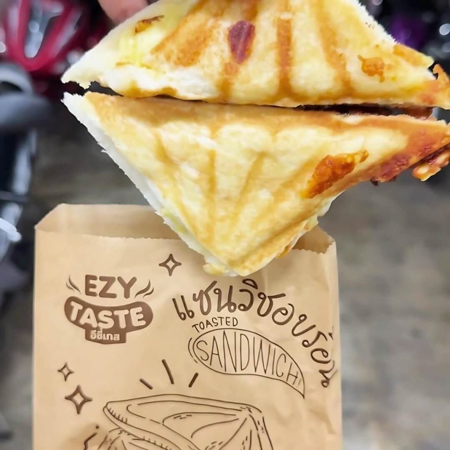 Kult-Snack in Thailand – 7-Eleven Cheese Toastie Frisch getoastetes 7-Eleven Cheese Sandwich in einer Papierverpackung in Pattaya
